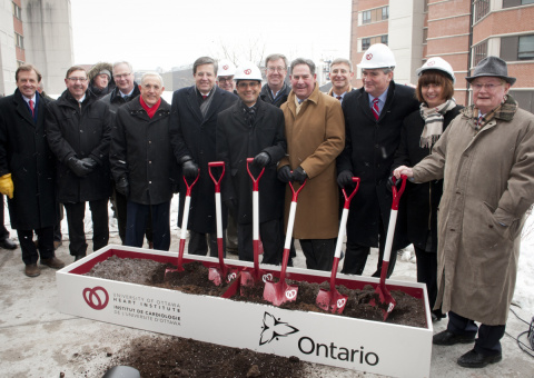 Political dignitaries and institutional leaders pose for a picture at an official groundbreaking ceremony.